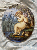 
													Médaillon ovale céramique polychrome figurant un putto dans les roseaux
												